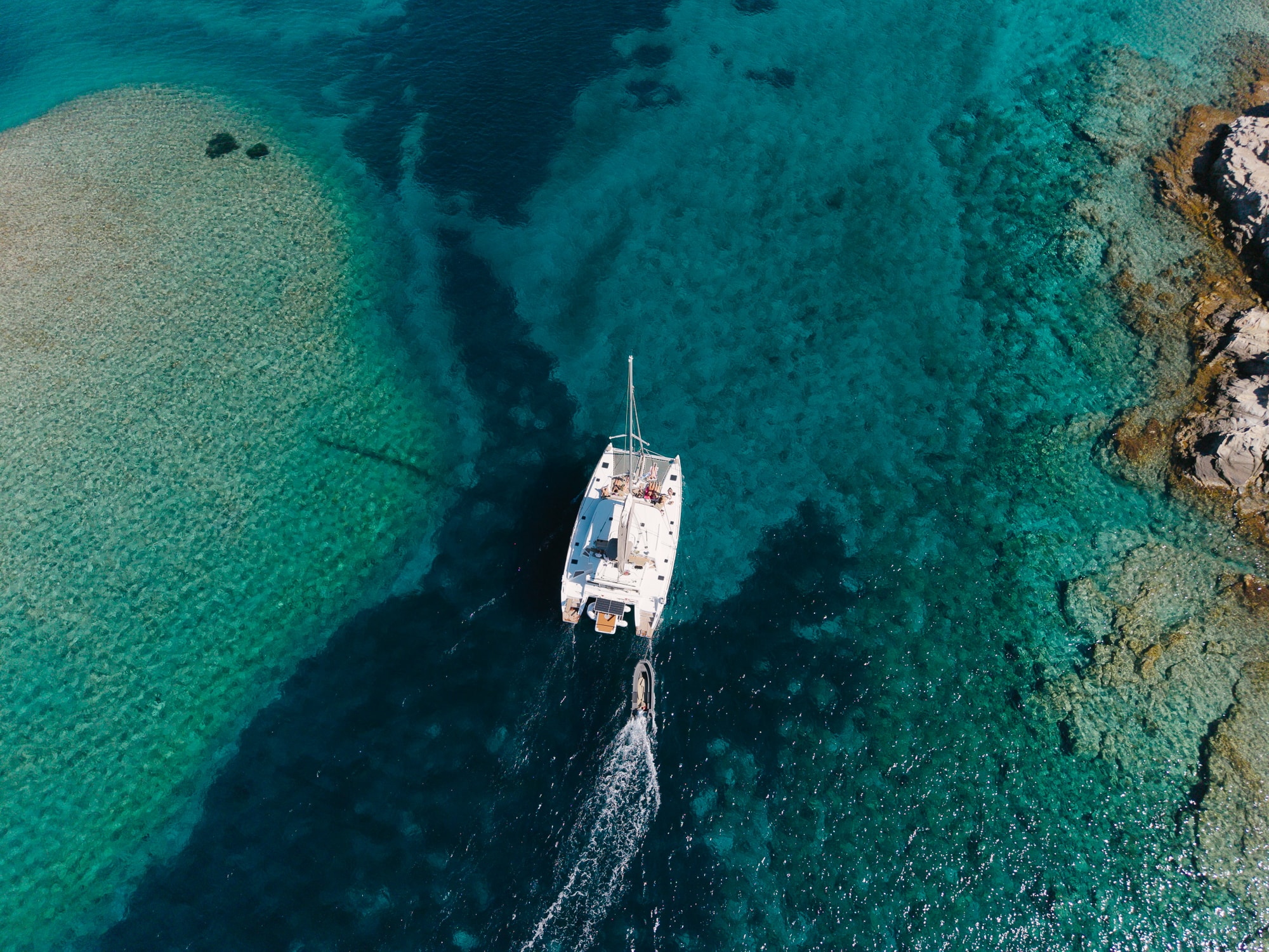 The Boho Experience catamaran with guests aboard, anchored off Delos, Mykonos